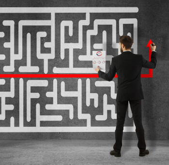 Businessman drawing a red line through a maze on a wall, symbolizing the strategy for navigating cybersecurity for small businesses.